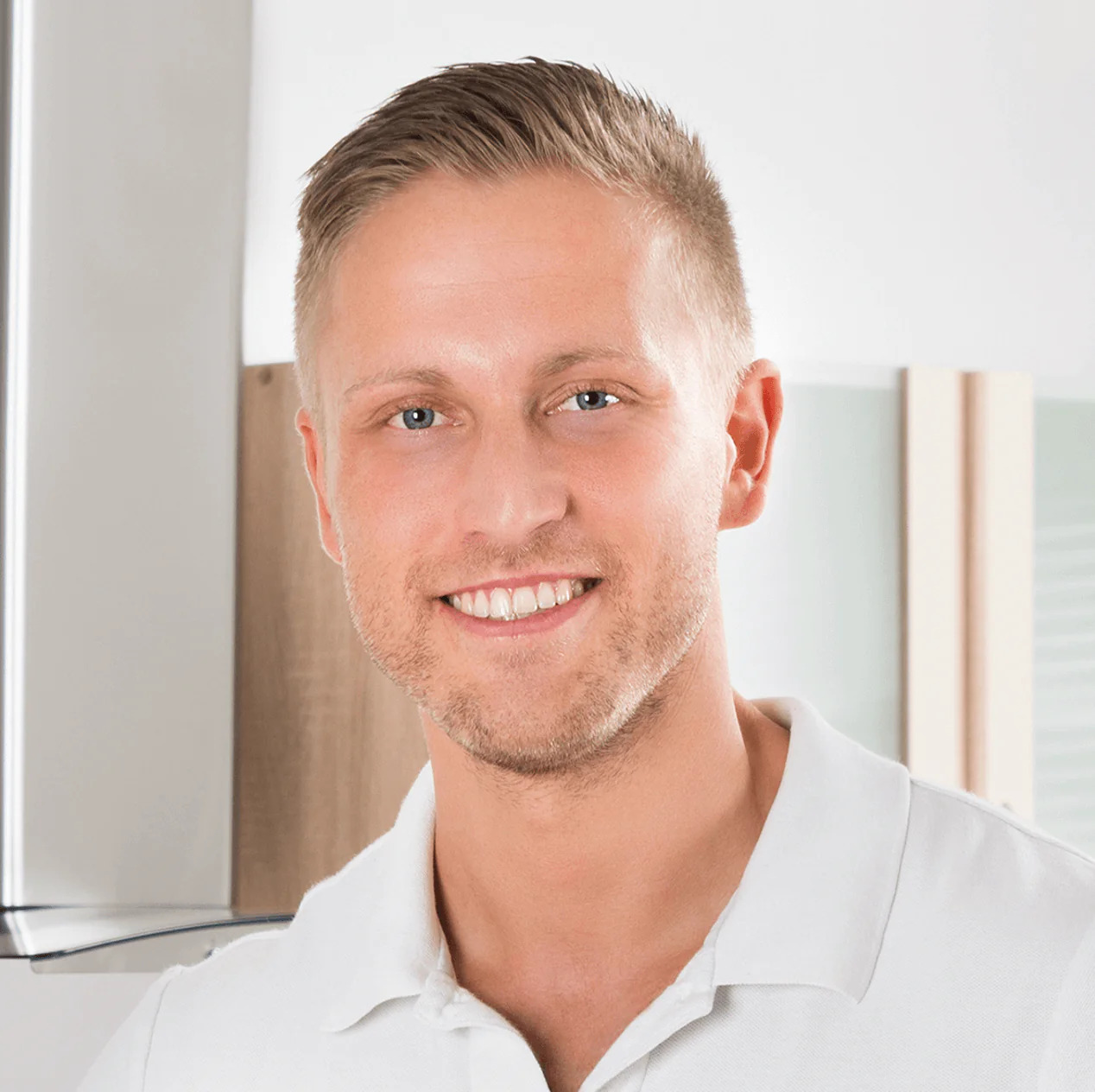 A man with blonde hair and blue eyes smiling.