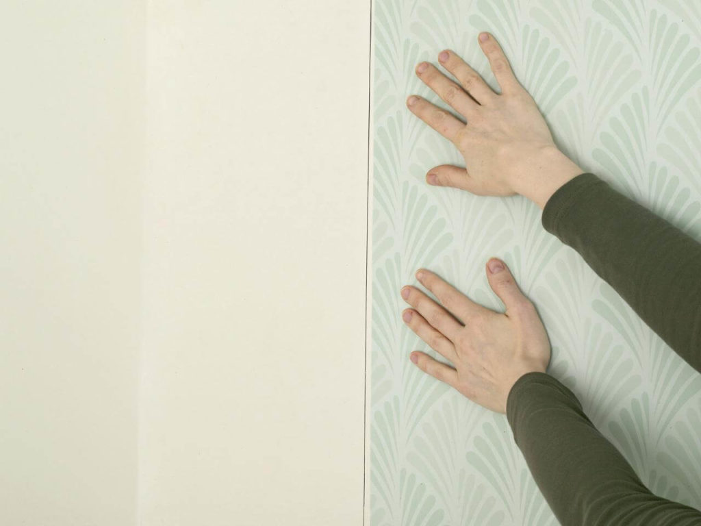 A person 's hands reaching up to touch the wall.