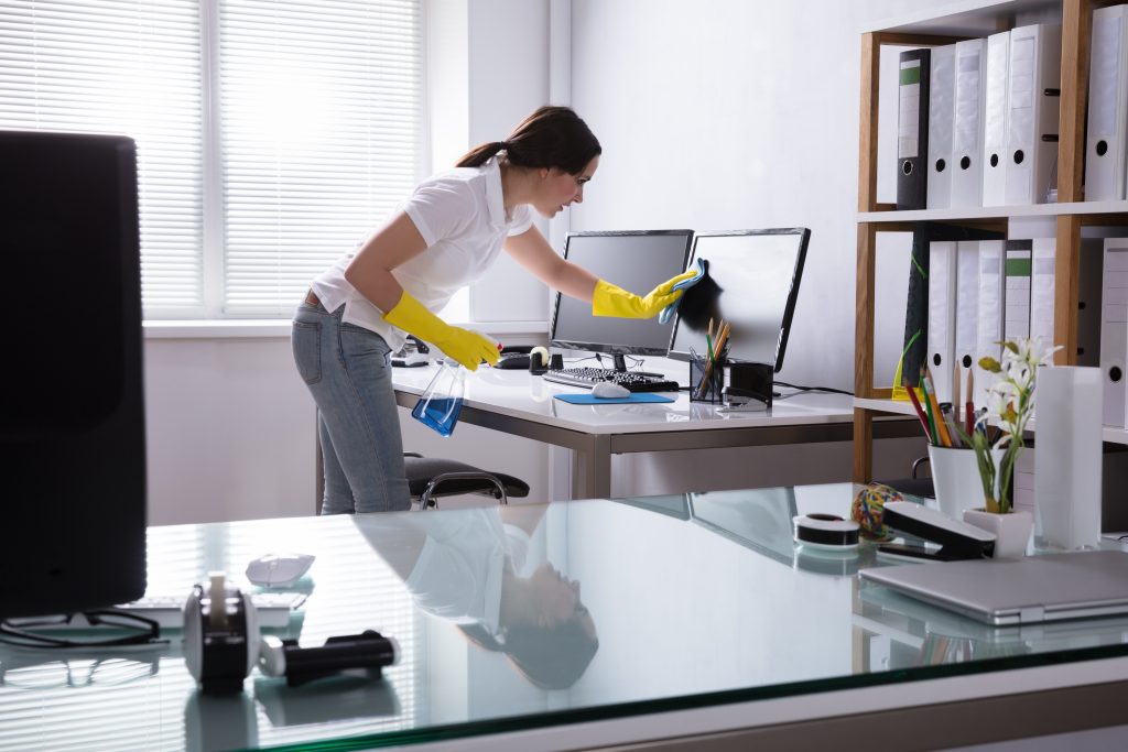 A woman in yellow gloves cleaning the desk.