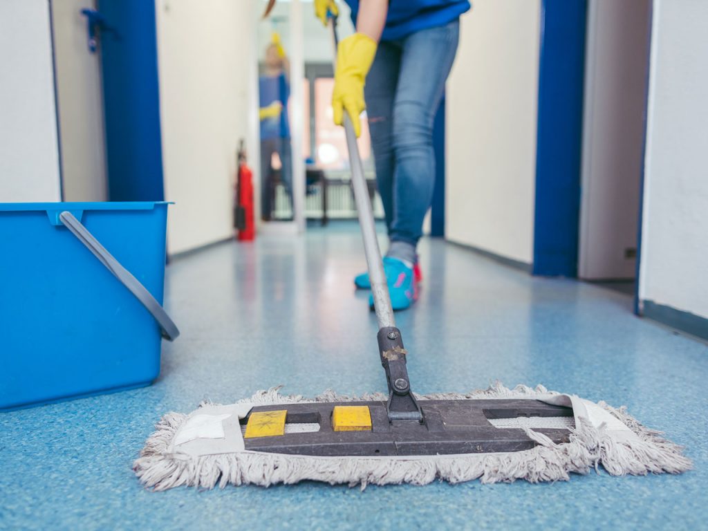 A person with yellow gloves and mop in the floor.