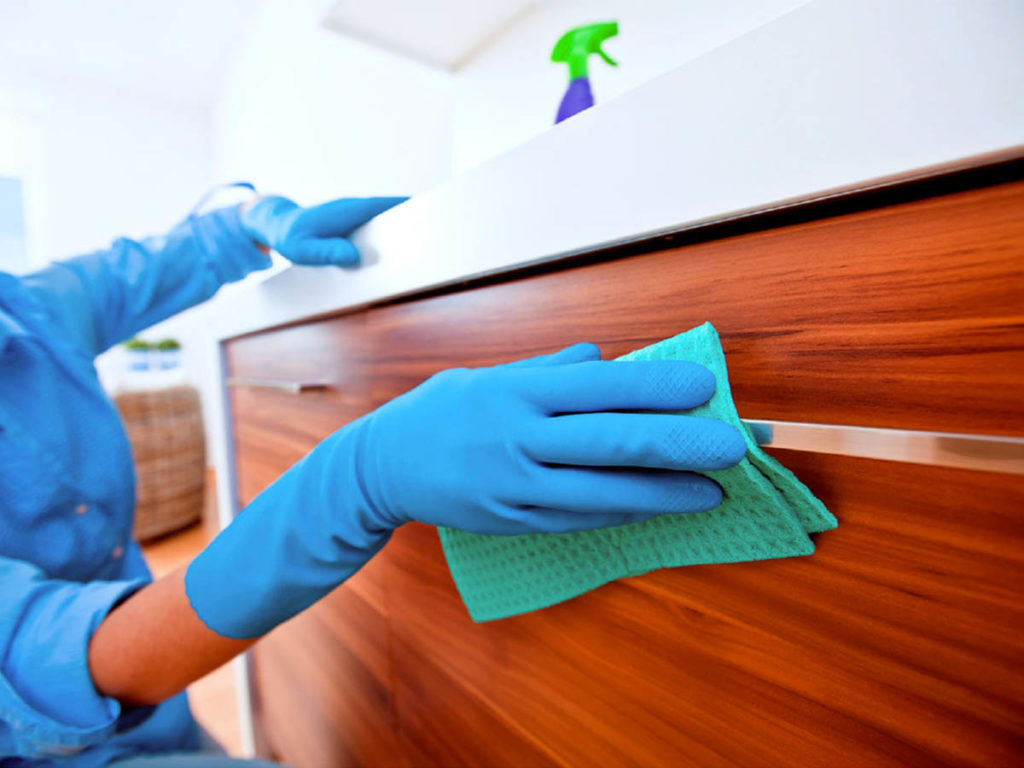 A person wearing gloves and cleaning the cabinets