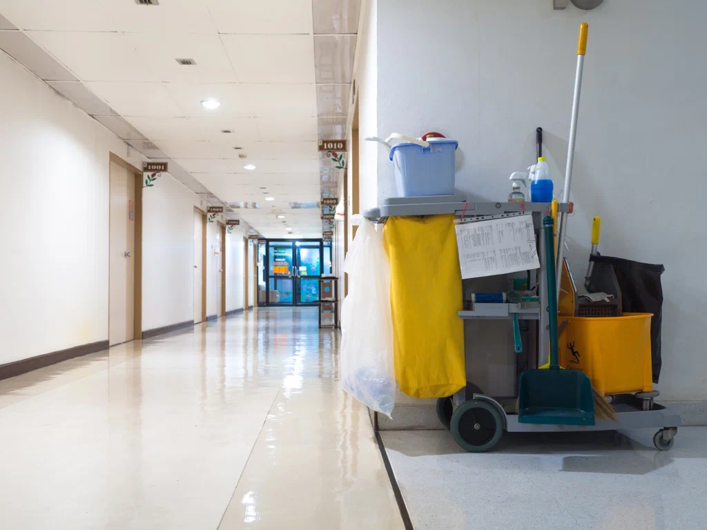 A cleaning cart in the middle of an empty hallway.