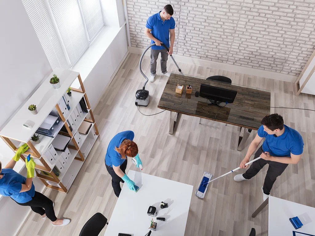 A group of people cleaning the floor with mops and brooms.