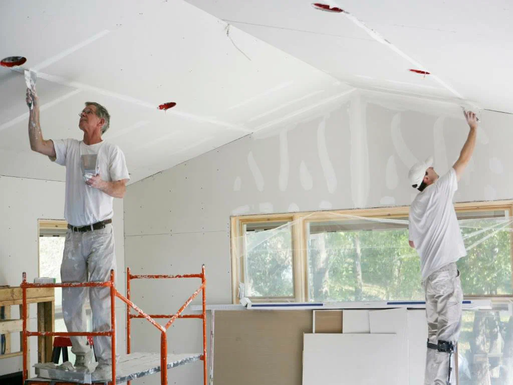 Two men are working on a room in the house.