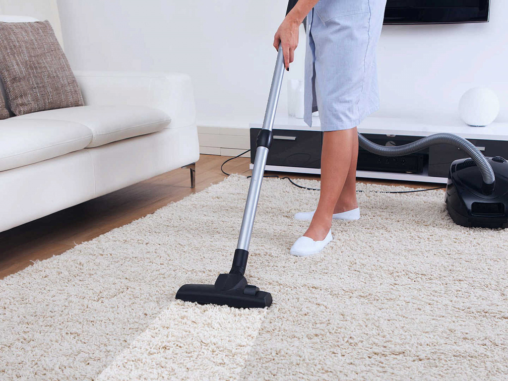 A person vacuuming the floor of their living room.