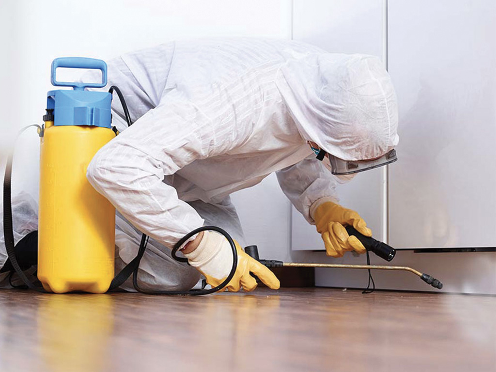 A person in white suit and yellow gloves cleaning floor.