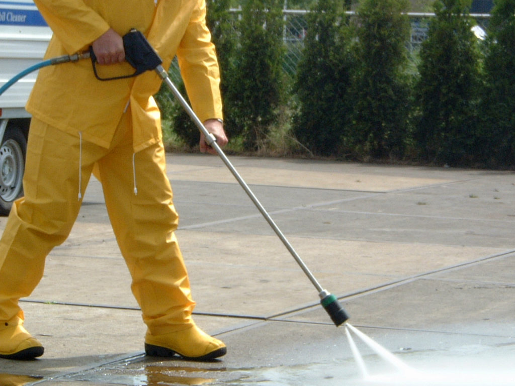 A person in yellow and black working on a driveway.