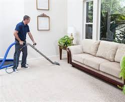 A man is vacuuming the floor of his living room.