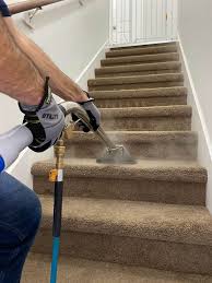 A person using a power washer to clean stairs.